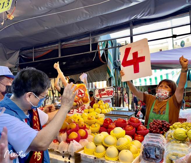 新竹縣長候選人楊文科（左）到竹東市場掃街拜票，攤商拿出準備好的看板高呼凍蒜。（楊文科團隊提供／邱立雅竹縣傳真）
