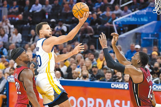 勇士射手史蒂芬柯瑞（右）飛身挑籃，熱火前鋒吉米巴特勒阻擋不及。（美聯社）