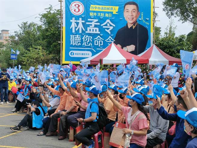 台中市议员林孟令力拼连任，30日上午在龙井举办问政说明会，涌入现场的乡亲几乎坐满整条街，一同摇旗支持。（潘虹恩摄）