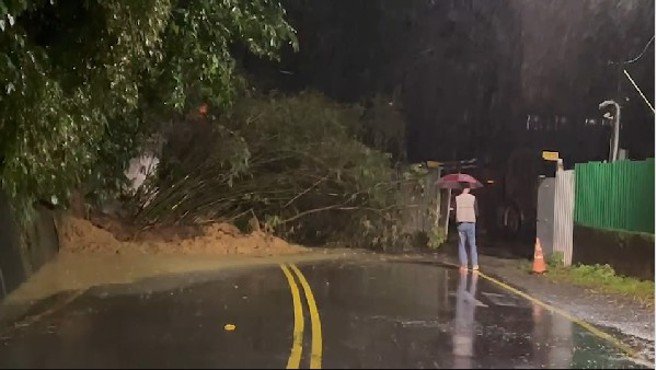 基隆七堵2处土石崩落紧临附近社区，警消紧急调派挖土机清理开通道路。（翻摄照片）