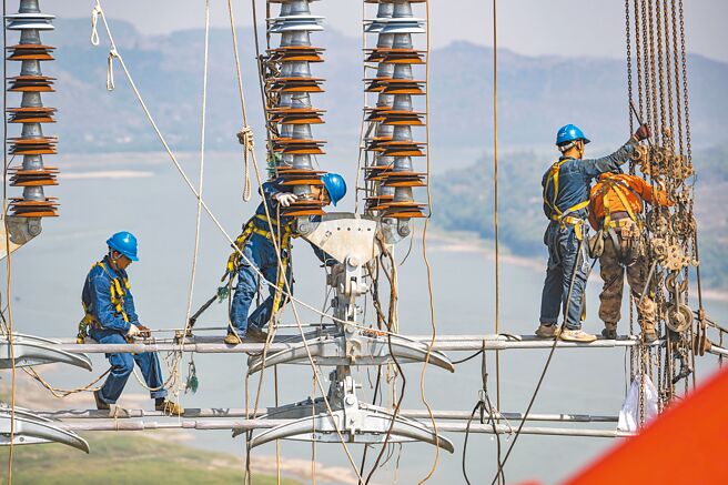 大陸國務院副總理韓正表示，今冬能源保供穩價「具備了較好的基礎」，強調保障民眾溫暖過冬，絕不允許發生「拉閘限電」。圖為大陸工人建設輸電網路。（中新社）