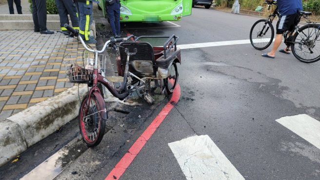 婦人的電動三輪車疑似撞到斜坡路緣石導致爆炸起火，整輛車被燒毀，停在一旁的客運車頭也被波及。（翻攝照片）