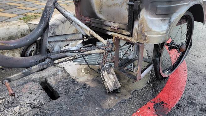 婦人的電動三輪車疑似撞到斜坡路緣石導致爆炸起火，整輛車被燒毀，停在一旁的客運車頭也被波及。（翻攝照片）