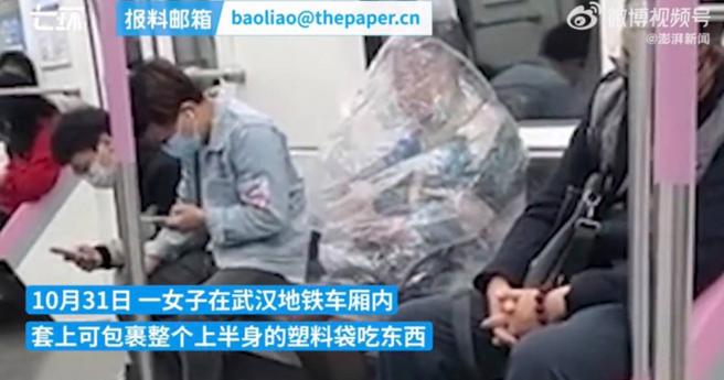 大陆一名女子日前被发现在地铁车厢内吃东西，不过她上半身套了个超大透明塑胶袋，相当引人注目。（图／翻摄澎湃视频）