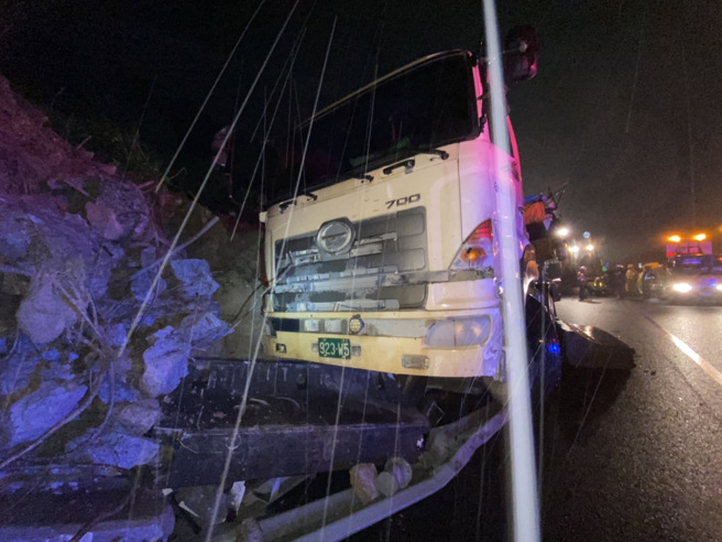 國道1號汐止交流道今晚邊坡再度坍落，土石滑落波及施工的砂石車。（新北市消防局提供）