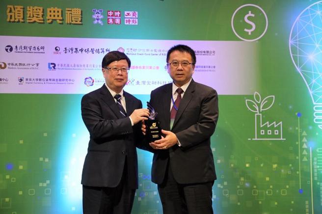 （群益证在「数位金融奖」获一金二优佳绩，总经理李文柱(右)自期交所董事长吴自心手中接过「绿色数位金融奖」金质奖座。图／群益金鼎证券提供）