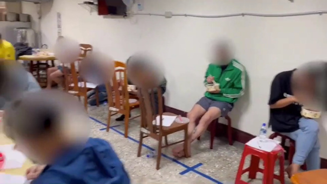 26名男女在诈骗集团控制下每天仅能共吃1碗泡麵，诈团甚至还在泡麵内放毒品，如今获救后，受害者安心在警局吃便当。（翻摄影片）