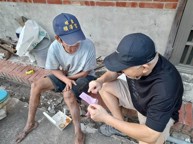 下營區公所人員今天將當月的實物兌換券給馮男（左），讓他在假日也能享用熱食。（下營區公所提供／李俊淇台南傳真）