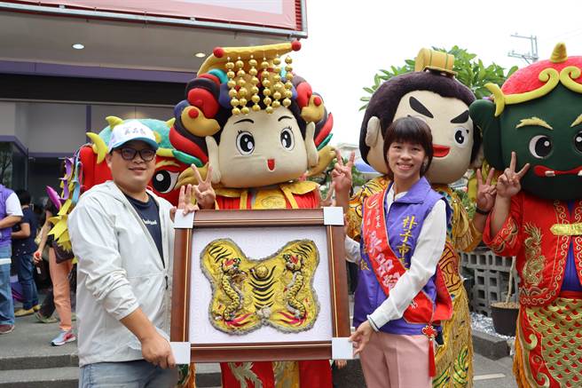 嘉义县无党籍朴子市长候选人吴品叡（右）争取连任，5日竞选总 部成立，嘉义县刺绣文化学会理事长周让廷（左）特地送上炮炸过的虎爷神明衣，祝福她挺过抨击、顺利连任。（吕妍庭摄）