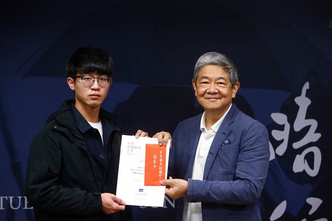 「年度最佳新聞照片」的翁睿坤以詩意的手法，拍攝台鐵太魯閣號行經花蓮大清水隧道時，因撞擊侵入路線的工程車出軌，造成大死傷，隔日家屬赴現場招魂的畫面。翁睿坤（左）從評審林樂群（右）手中接下獎狀及獎金。（鄧博仁攝）