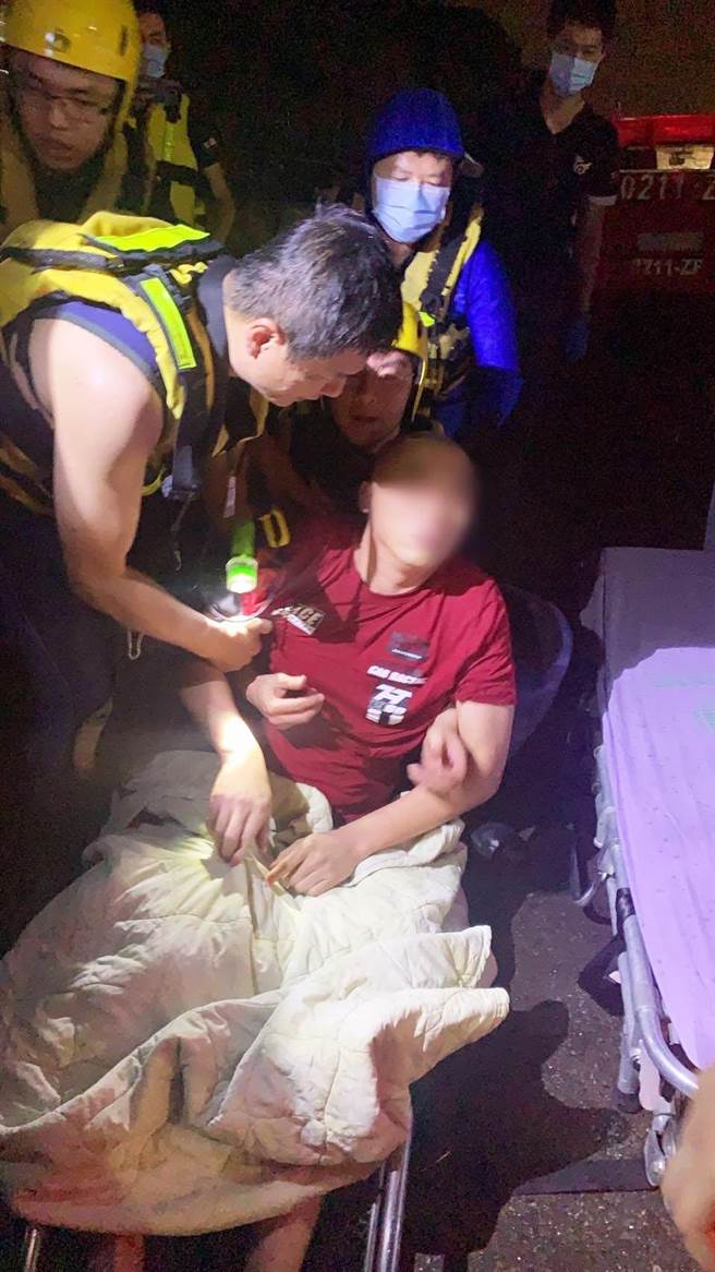 台中港务消防队员在消波块旁，紧急救起张男将他送医。（台中港务消防队提供）