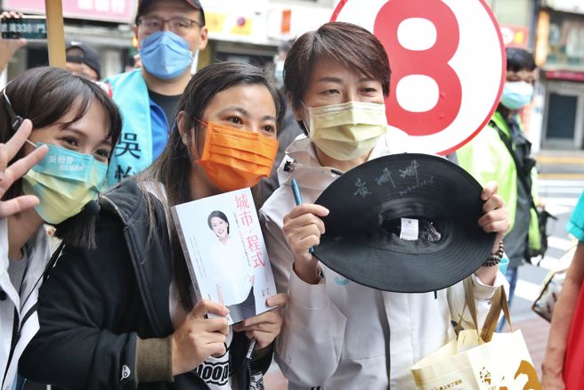 台北市长候选人黄珊珊（右）8日走访艋舺服饰商圈，有民眾热情的拿出黄珊珊的传记与帽子请她签名。（杜宜谙摄）