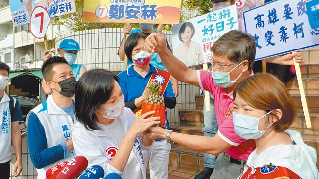 国民党高雄市长候选人柯志恩（前左）8日到凤农市场扫街，支持者送凤梨预祝当选。（柯宗纬摄）