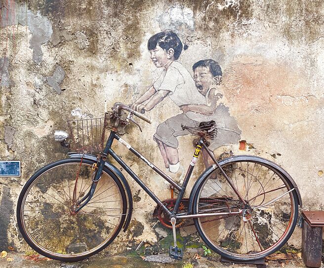 喬治市常吸引許多旅客到訪，立陶宛畫家爾納斯壁畫更成為拍照打卡熱點，圖為畫作《姐弟共騎》。（吳娮翎攝）