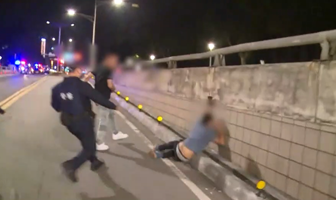 後車的4男1女肇事逃逸後又返回現場，竟當場與拍攝的記者起衝突，一男飆髒話吼「拍什麼東西啊」並推倒一名記者，另一男衝上前嗆聲立刻遭強勢逮捕。（李文正翻攝）