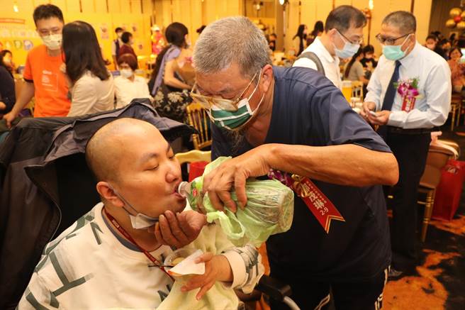 邹茂琳拉拔罹患重度自闭症的儿子32年，即使在表扬会场仍细心照料。（新北市社会局提供）