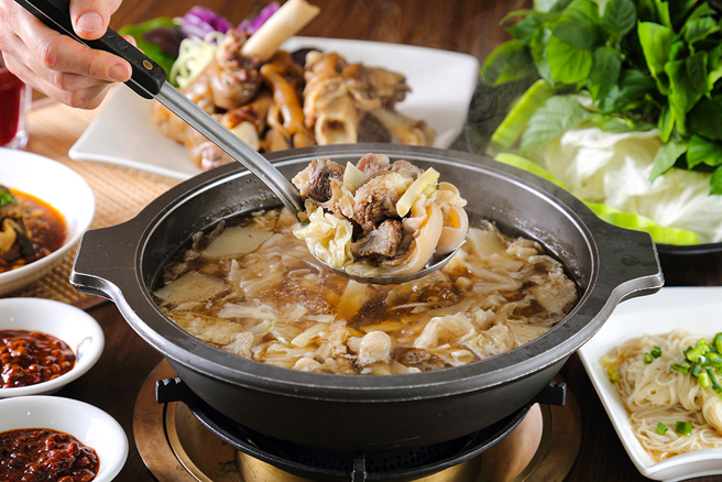 加入甘蔗熬煮的汤头是羊肉炉的灵魂，滋补暖身、醇香甘甜，随锅赠送的羊大骨已成为店家特色。(摄影/Carter)