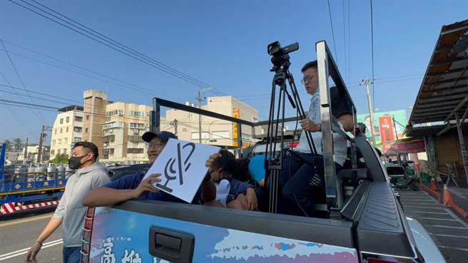 今天柯志恩的前导车上的幕僚，特地拿出手举牌，上头印有「麦克风消音」图案，以及「乖啦」，提醒柯志恩小心注意言行，都有可能从直播当中放送。（柯宗纬摄）