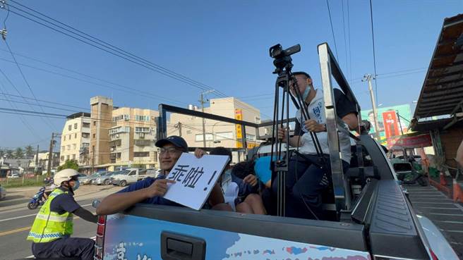 今天柯志恩的前导车上的幕僚，特地拿出手举牌，上头印有「麦克风消音」图案，以及「乖啦」，提醒柯志恩小心注意言行，都有可能从直播当中放送。（柯宗纬摄）