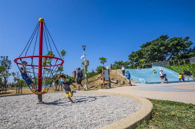 竹北市AI綠能公園，小朋友快樂玩旋轉陀螺和大碗公滑梯。（羅浚濱攝）