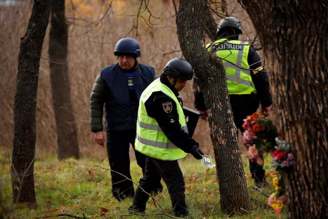 乌克兰警方与法医16日在赫松寻找俄军攻击乌克兰人的证据。（图／路透社）
