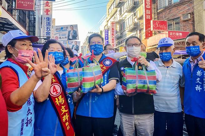 国民党新竹县长候选人杨文科（中左）和争取连任的议长张镇荣（中右），19日到新丰市场拜票，热情摊商热情送上肉粽和蒜，祝福「包中」、「冻蒜」。（罗浚滨摄）