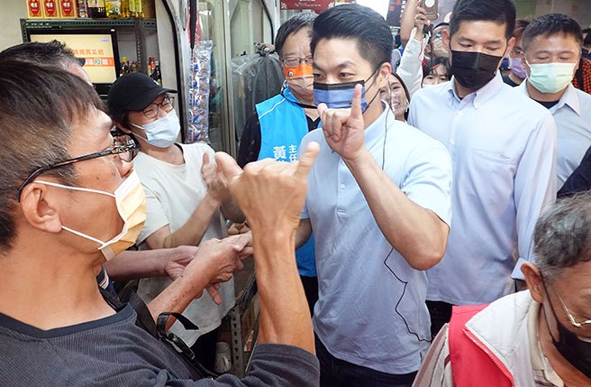 国民党台北市长候选人蒋万安（中右）19日前往永乐市场拜票，并与支持者互比6号的手势。（姚志平摄）