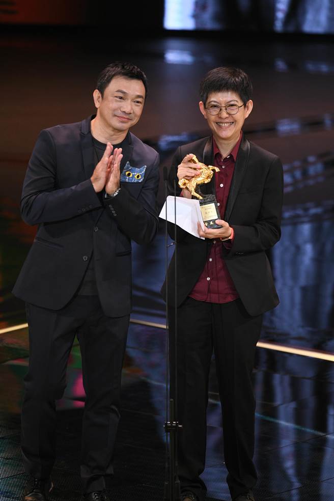 張照堂低調隱身於台下，由弟子曹文傑（右）從導演黃信堯手上領過獎項。（金馬執委會提供）