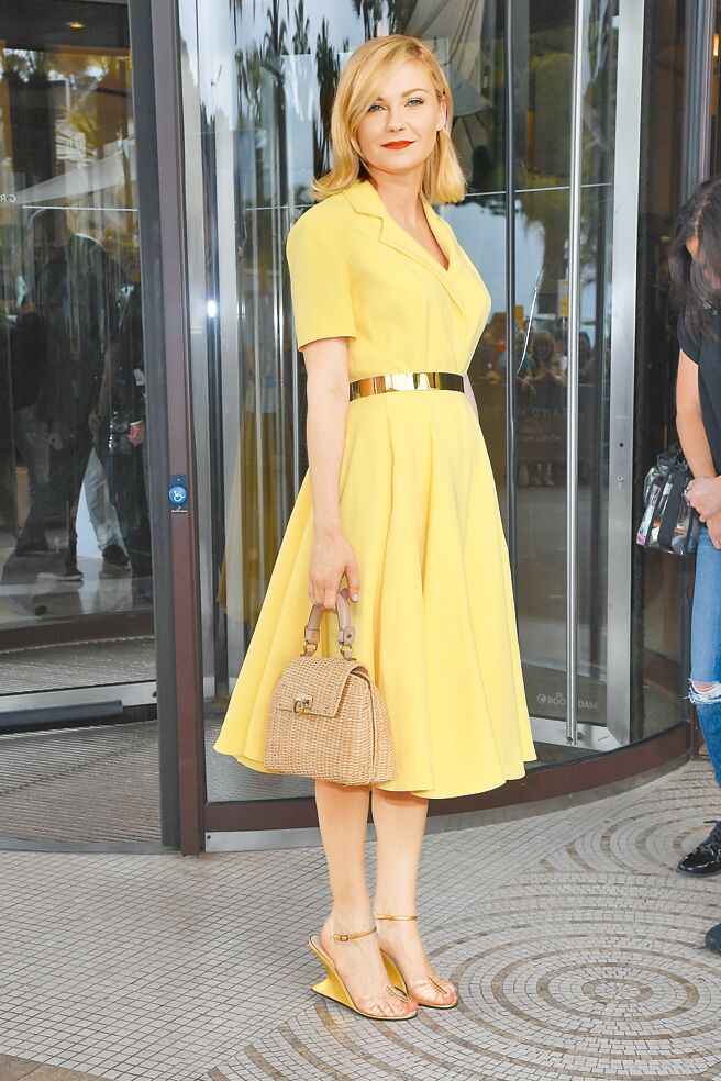 美国女星克丝汀邓斯特穿着Ferragamo Creation系列金色隐形鞋及手拿Sofia藤编提包现身坎城街头。（FERRAGAMO提供）