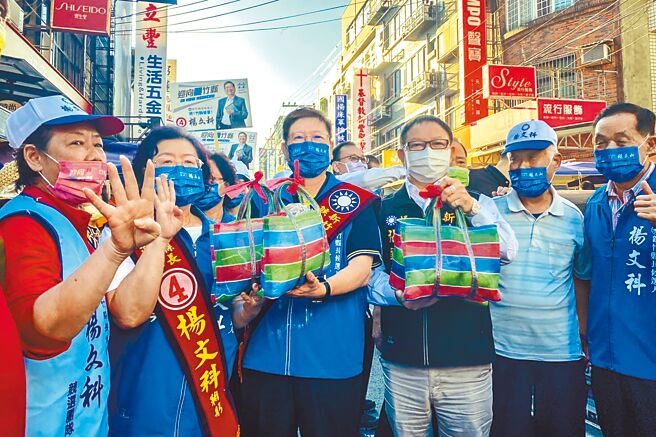 国民党新竹县长候选人杨文科（中左）和争取连任的议长张镇荣（中右），19日到新丰市场拜票，热情摊商热情送上肉粽和蒜，祝福「包中」、「冻蒜」。（罗浚滨摄）