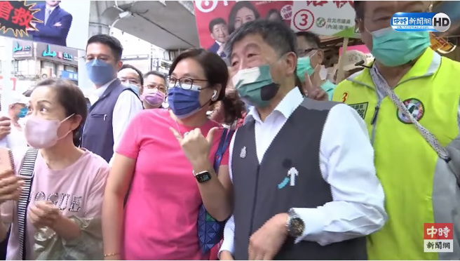 民进党台北市长候选人陈时中20日至湖光市场扫街拜票，一名女子与他合照时，却摆出国民党市长候选人蒋万安的6号手势。（图／截自中时新闻网YT）