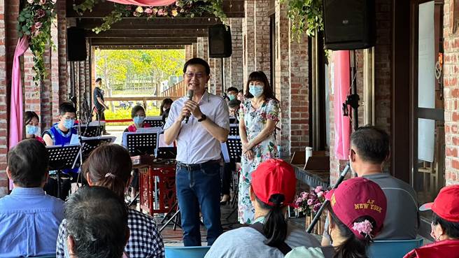 台中市客家事务委员会主委江俊龙于花圃前与国乐团团员合影留念。（台中市客委会提供／陈淑娥台中传真）