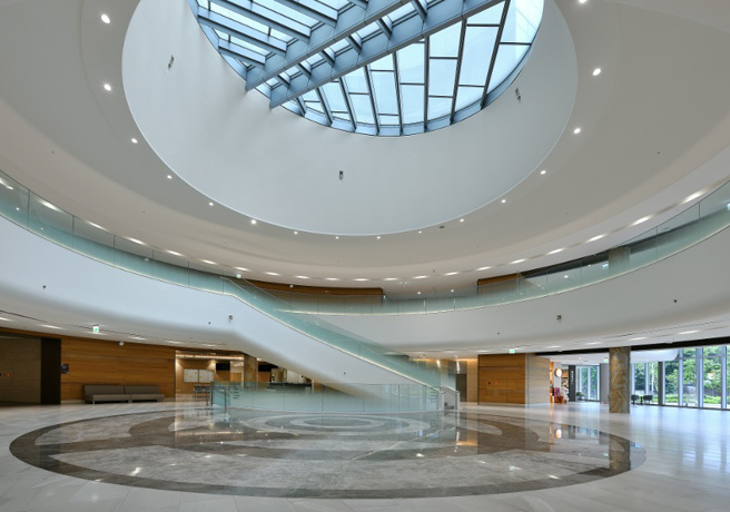 臺大癌醫大廳陽光自然灑落，石材牆面與木紋飾條，讓踏入的病友與家屬們彷彿漫步山林。（圖/ 遠見提供）