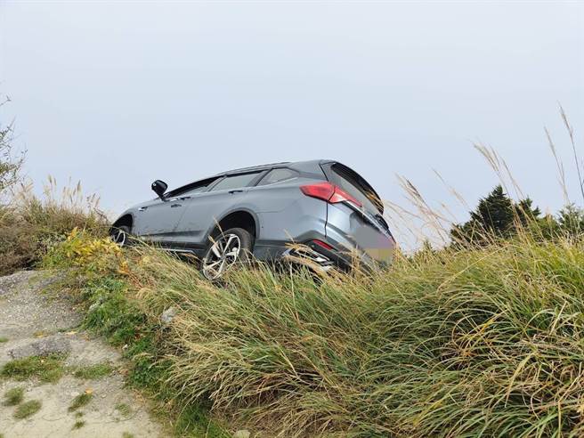 來自高雄劉姓女子昨與丈夫駕車赴合歡山，未料倒車力道過大，車子衝出懸崖，被邊坡草堆樹木卡住，以致半個車身呈現傾斜狀態，吊掛在懸崖旁，畫面相當驚險。（新城警分局提供／羅亦晽花蓮傳真）