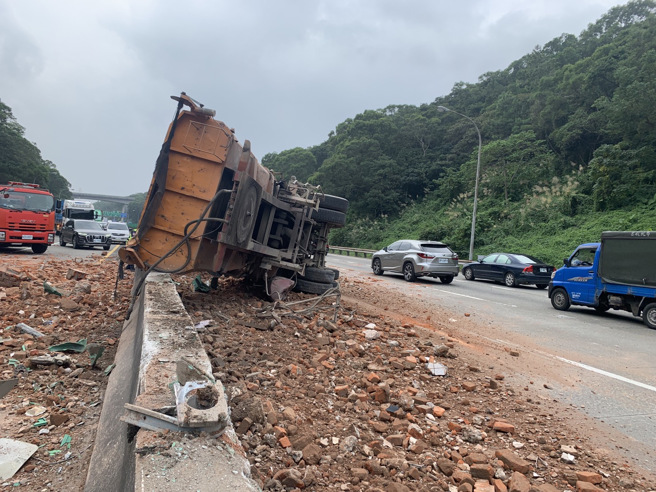 国三北上龙潭段22日中午发生车祸，一辆大货车撞上中央护栏后翻覆，现场满地土块。（翻摄脸书《国道公路警察局》）