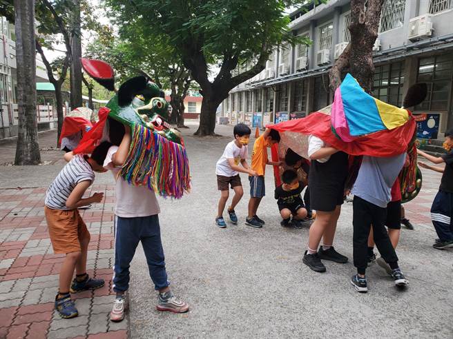 小朋友拿着自己亲手捏塑、糊纸、彩绘而诞生的狮头舞动，显得非常有感情，爱不释手。（周丽兰摄）