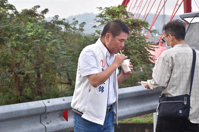 苗栗县长候选人锺东锦一早起床就忙着电话固票，连早餐都是站在路边吃。（谢明俊摄）
