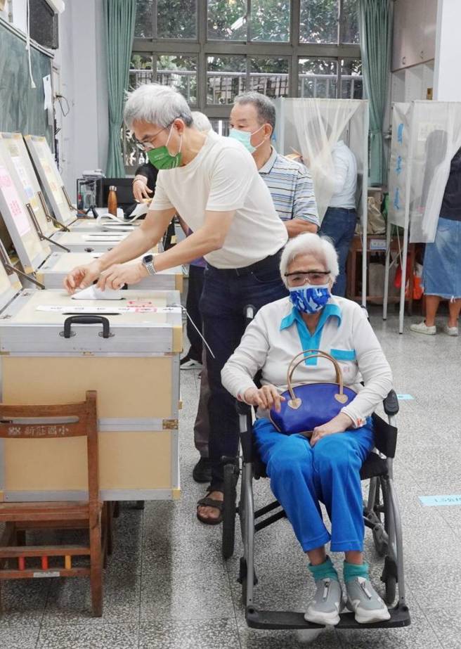 九合一選舉上午開始投票，坐輪椅年長選民由家人陪同投票。（黃子明攝）