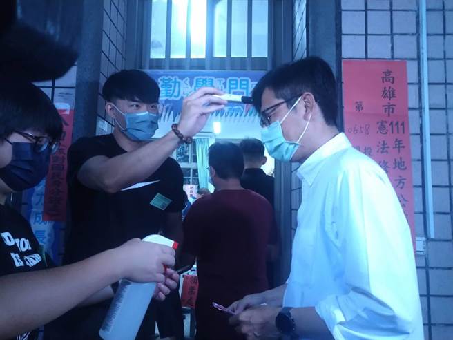 高雄市长陈其迈进入投开票所投票前，现场选务人员帮他量额温。(林雅惠摄)