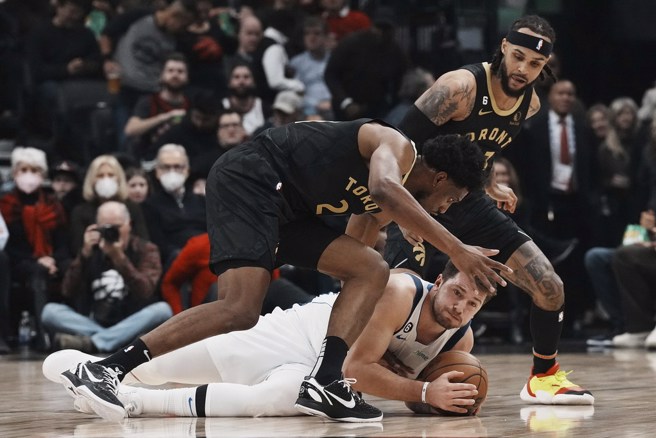 東契奇倒在地上拚命護球，一旁的桑迪斯楊(左)伺機搶球。(美聯社)