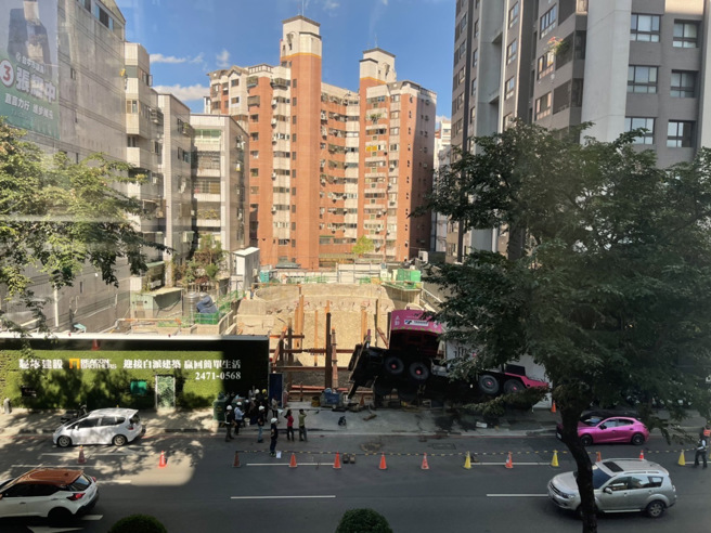 台中市西区五权西路一处建案28日发生工安意外，一辆吊车疑因操作不慎而吊臂砸入工地，整辆车悬空。（图／读者提供）