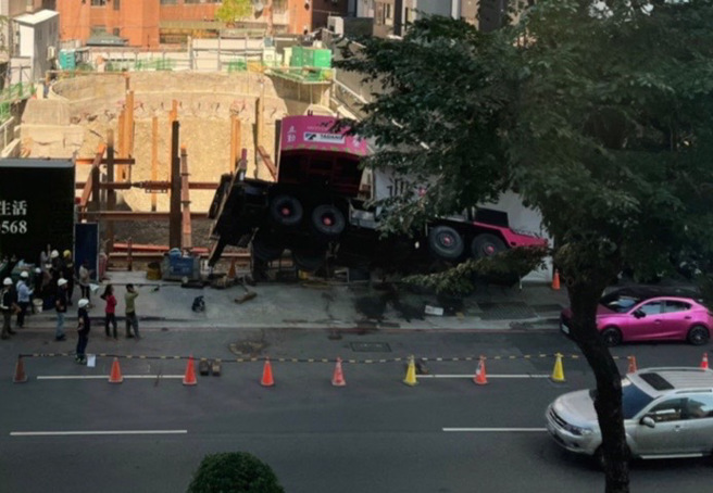 台中市西区五权西路一处建案28日发生工安意外，一辆吊车疑因操作不慎而吊臂砸入工地，整辆车悬空。（图／读者提供）