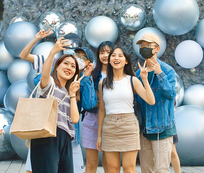 疫情趋缓，指挥中心28日宣布12月1日起，室外取消全程配戴口罩规定，餐饮场所也取消不得逐桌敬酒的规定。图为民眾在室外脱下口罩拍照留念。（陈君玮摄）