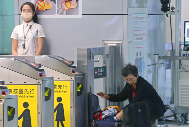 今开放室外免戴口罩，但进入室内仍要戴，一名乘客在车站出入口翻找口罩。（陈君玮摄）