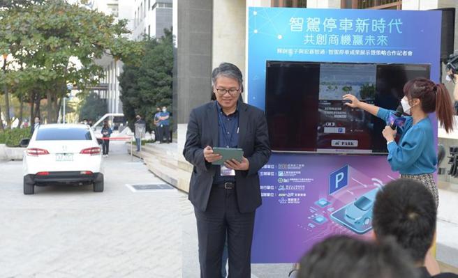 （经济部工业局副组长吕正钦(中立者)2日下午透过APP，远端操作「智慧自驾停车」解决方案，车体(左)能在无人驾驶下自动寻找车位停车。图／顏瑞田）