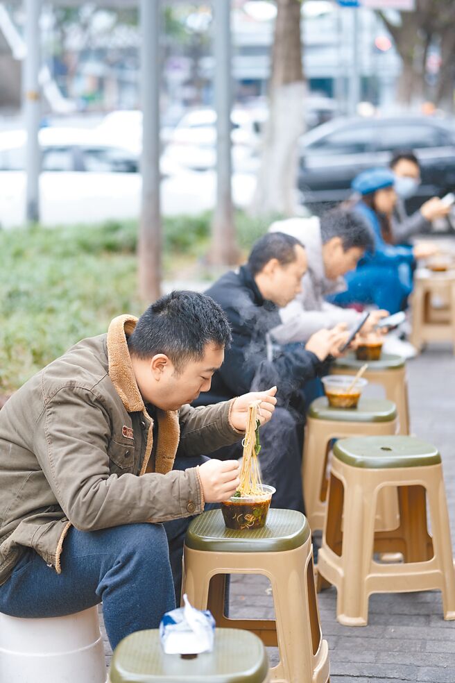 大陆日前发生封控示威后，多地不约而同放宽防疫限制，如重庆从全域协同防控调整为分区分类差异化防控。图为2日重庆南岸区一小麵馆外，市民可坐在户外吃麵。（中新社）
