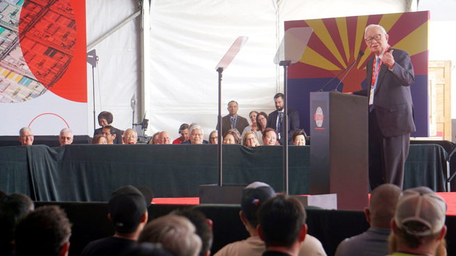 图为张忠谋6日在台积电亚利桑那州晶圆厂移机典礼上致词，苹果执行长库克等人在台下聆听。（图／中央社）