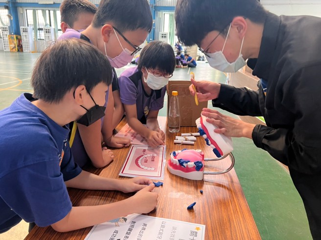 义守大学健管系学子，将口腔卫生卫教，以游戏的互动让国小学童更进一步学习正确的刷牙习惯。(照片/义守大学提供)