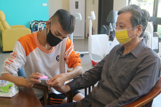 青年高中美容科的学生在老师带领下，拿出整套美甲工具，帮长辈们修指甲，两个学生一起服务，一个人服务一手。(照片/弘光科大提供)


