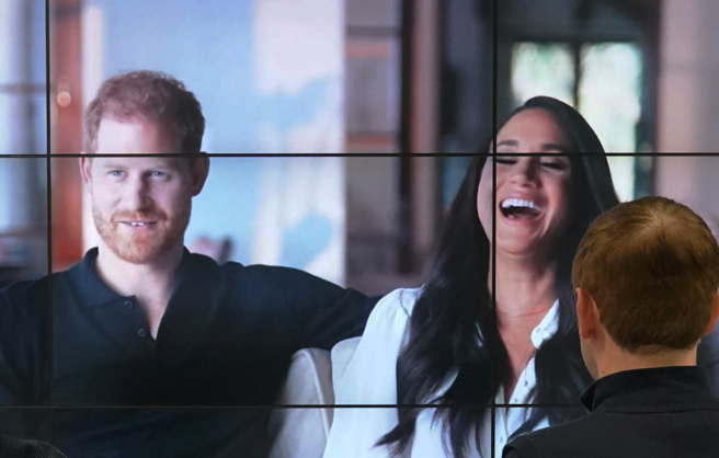 哈利和梅根的网飞（Netflix）新纪录片8日播出，上班族在伦敦的电视墙前观赏其中片段。（美联社）